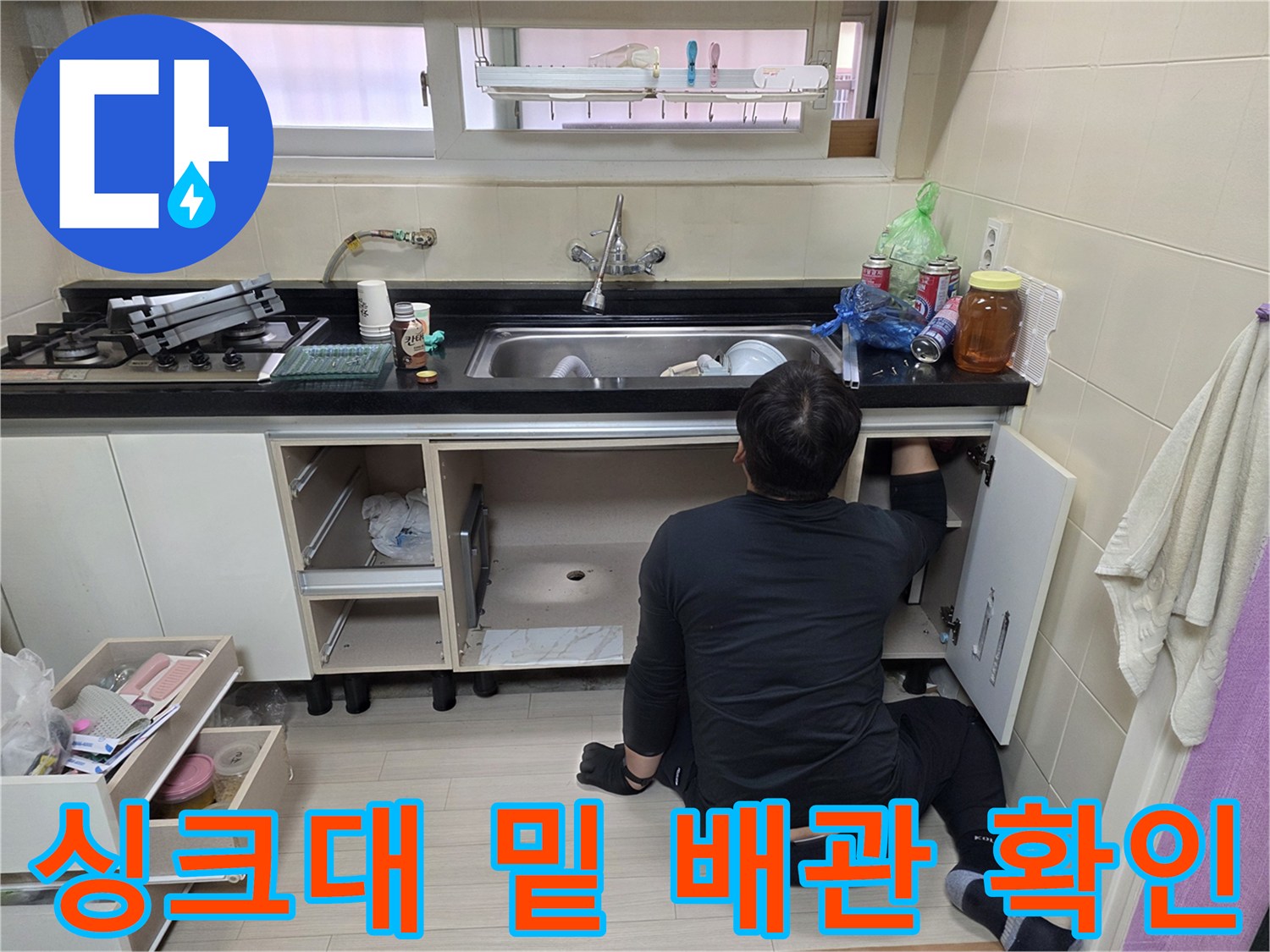 싱크대 하단 하부장 내부에서 바닥 배관을 점검하고 있는 작업자