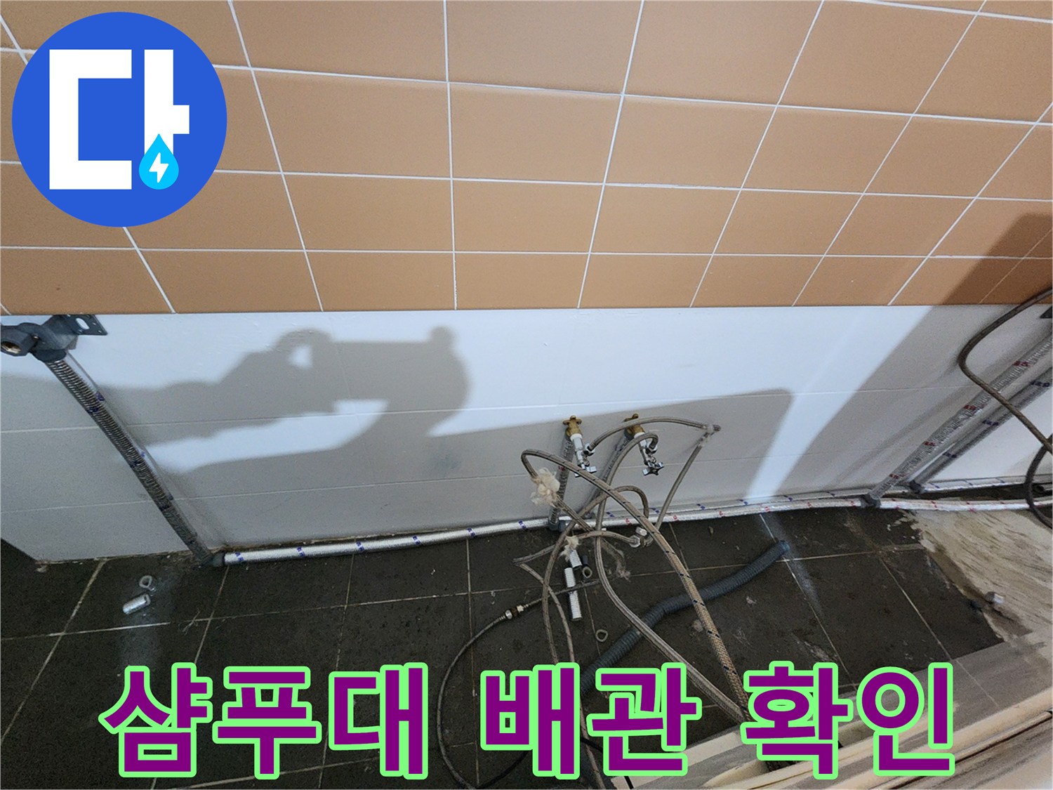 미용실 바닥 배관의 연결 부속과 타일 벽면 사이를 촬영한 사진입니다.