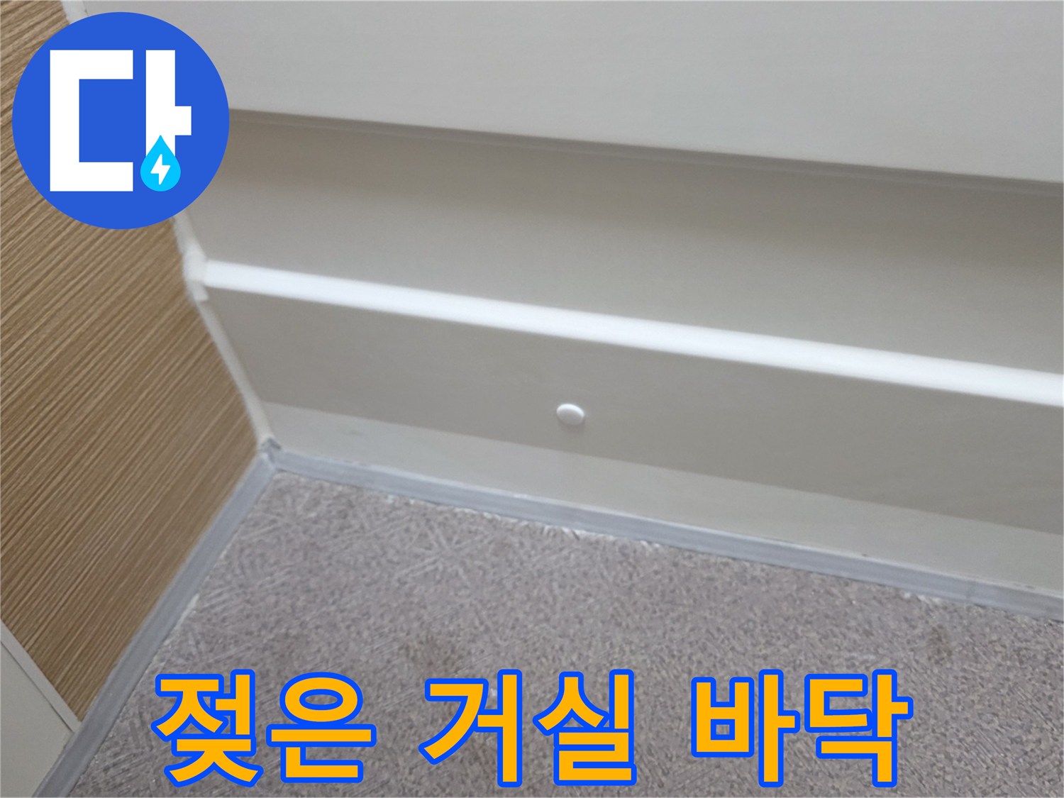 습기로 인해 눅눅해진 거실 장판과 벽면 하단부를 근접 촬영한 사진입니다.