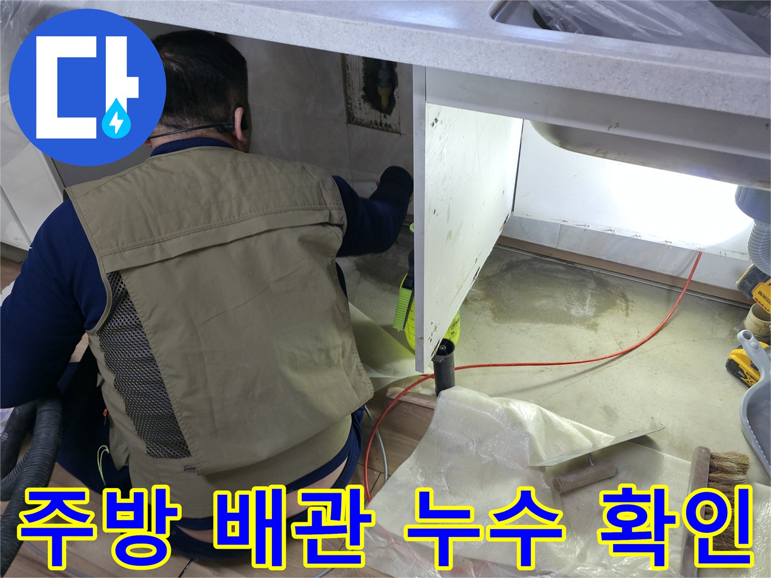 싱크대 하단 공간의 배관 상태를 점검하고 있는 엔지니어의 작업 모습
