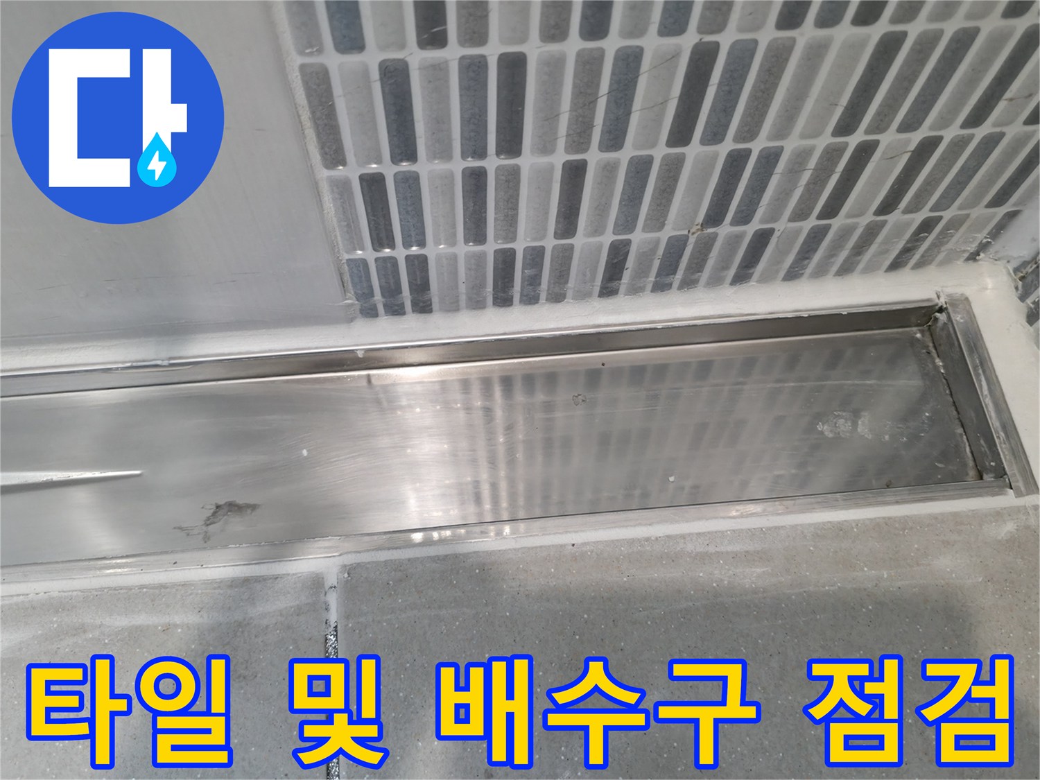 세로형 패턴 타일과 금속제 배수 트렌치의 교차 지점
