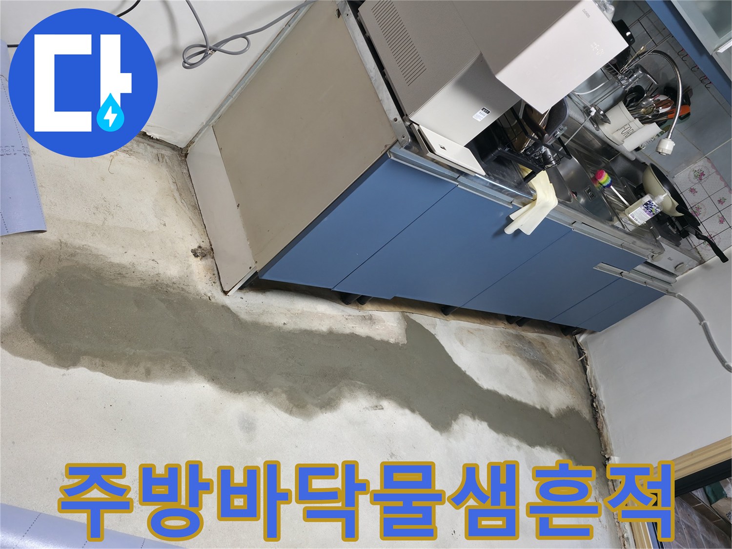 싱크대 하부 공간 바닥에 길게 남은 물샘 흔적과 방수 작업 부위