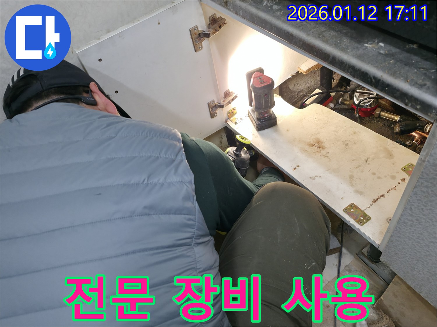 송파구 삼전동 누수 현장에서 - 누수 전문가가 전문 장비를 사용하여 싱크대 하부 누수 지점을 정확하게 탐지하는 모습입니다.