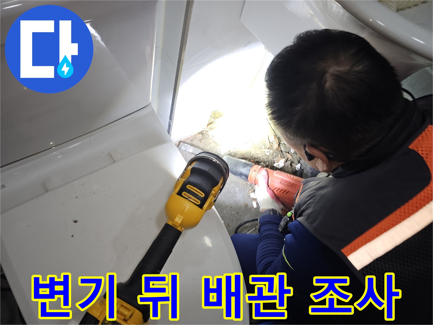 손전등을 사용해 변기 뒷벽의 배관 연결 부위를 집중적으로 살피는 중입니다.