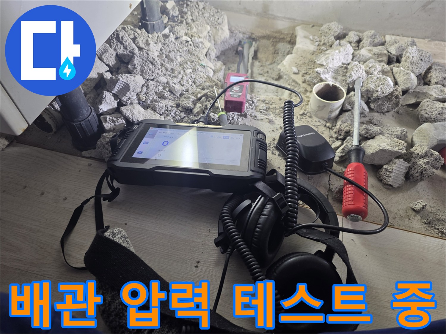 콘크리트 굴착 부위 근처에 놓인 누수 탐지용 디지털 장비와 헤드셋