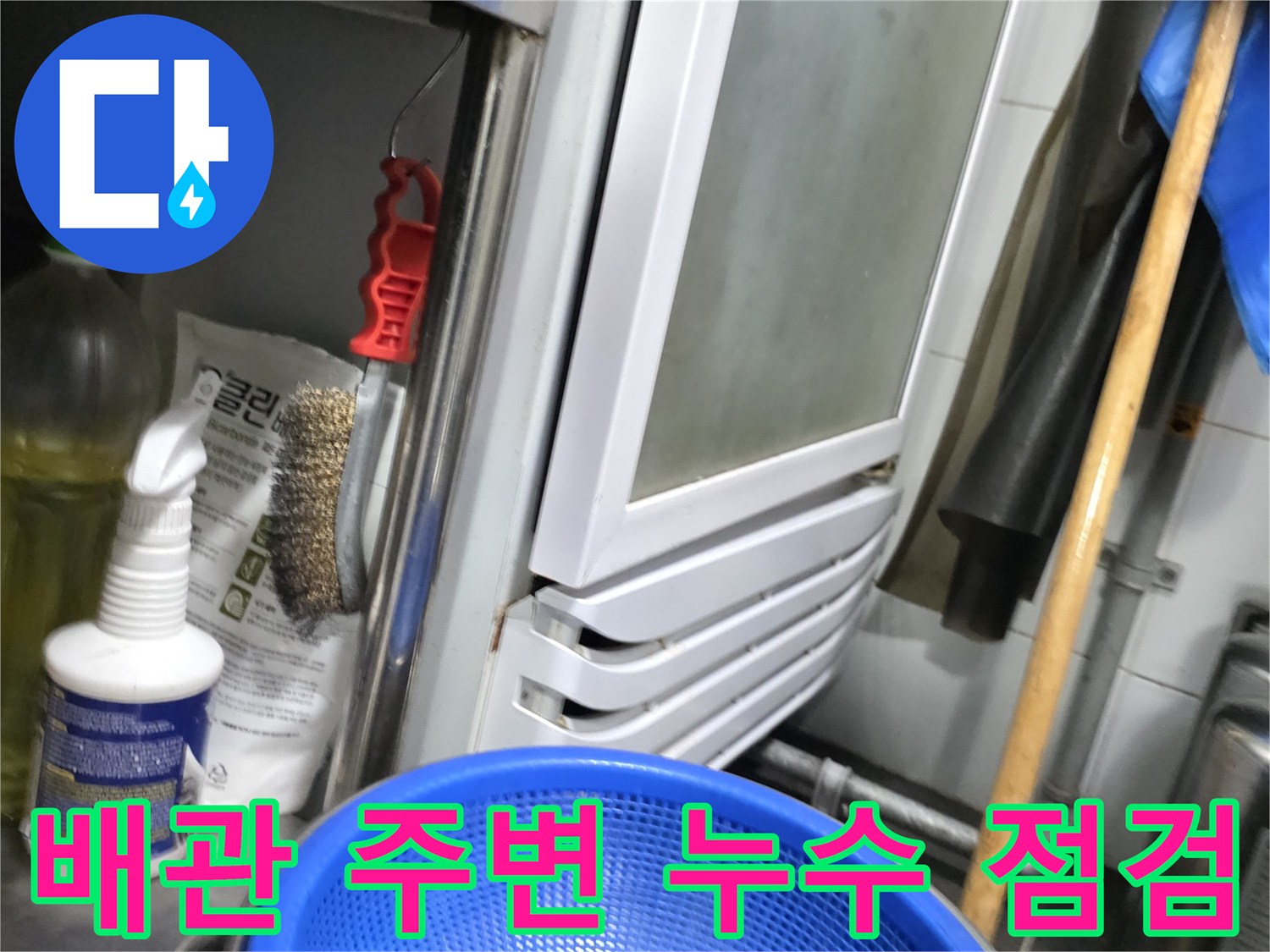 주방 온수기 아래 배관 연결부와 작업용 소품들
