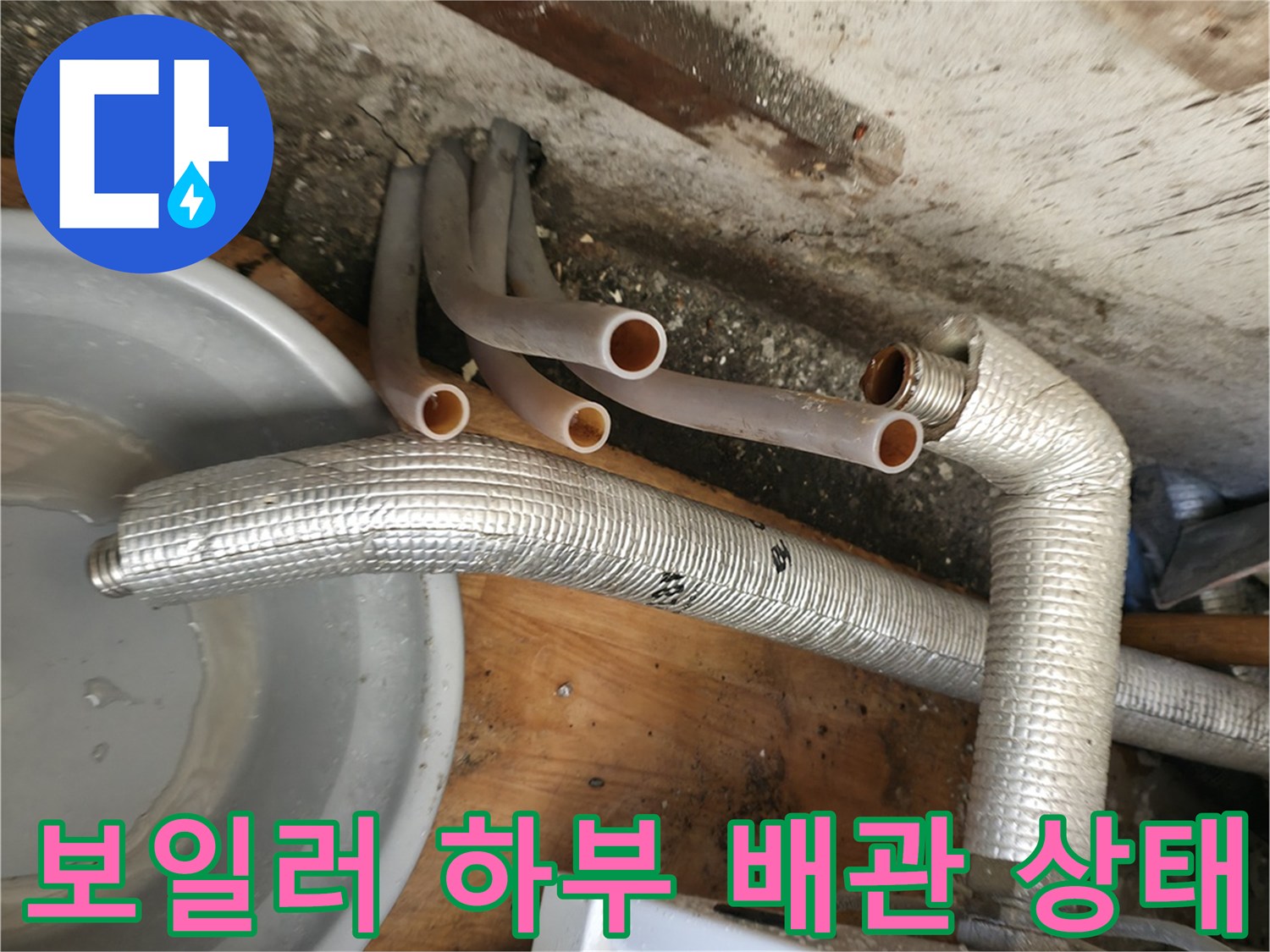 보일러 아래쪽의 노출된 배관들과 연결 부위를 근접 촬영한 모습입니다.