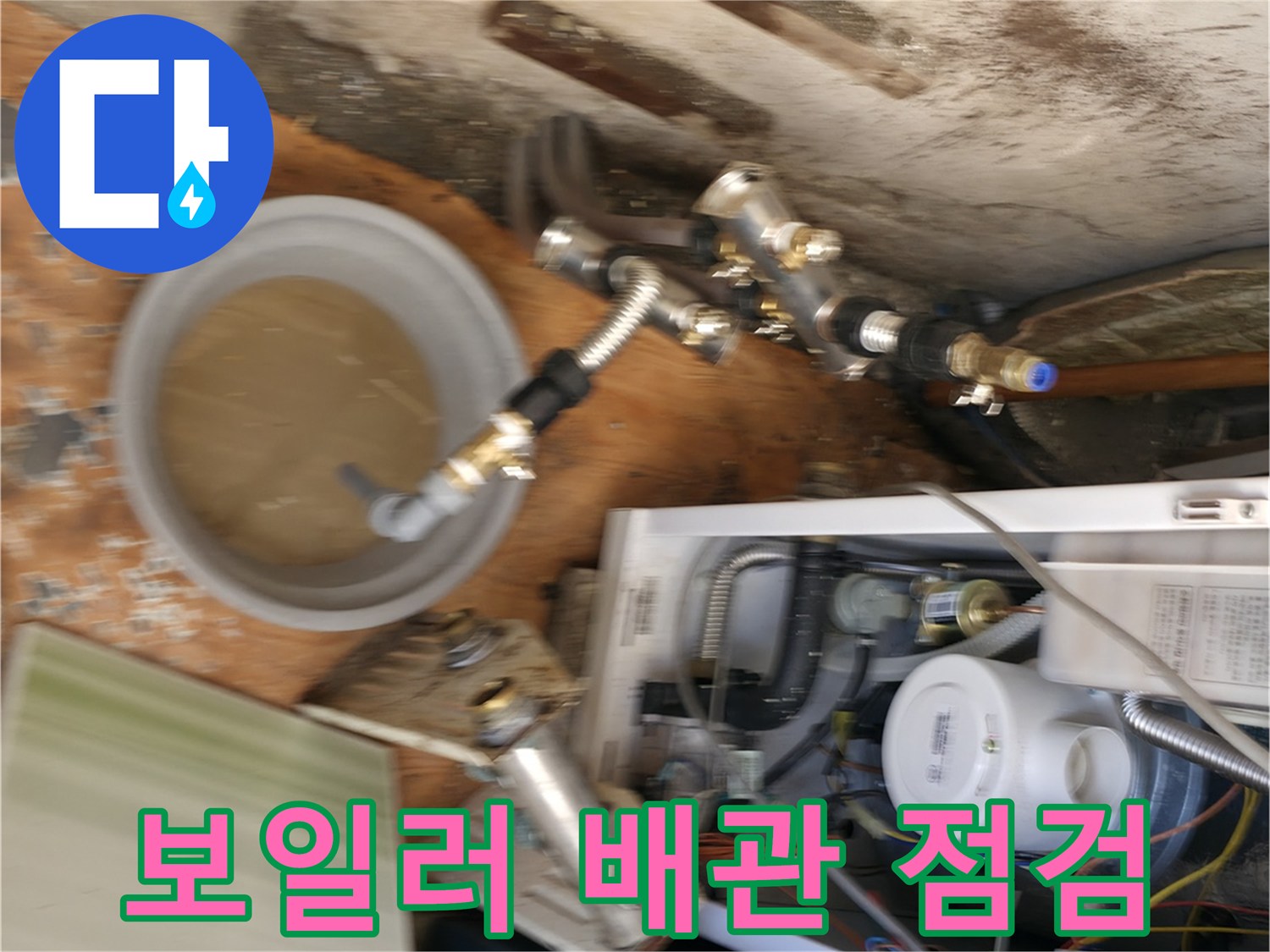 보일러 하단 배관 연결 부위와 물이 담긴 양동이 모습