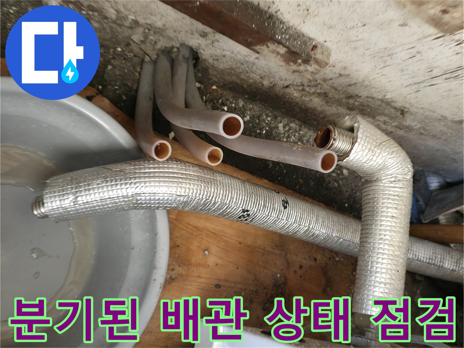 보일러 하단에 연결된 은색 보온재 관과 분지되는 엑셀 파이프의 모습입니다.