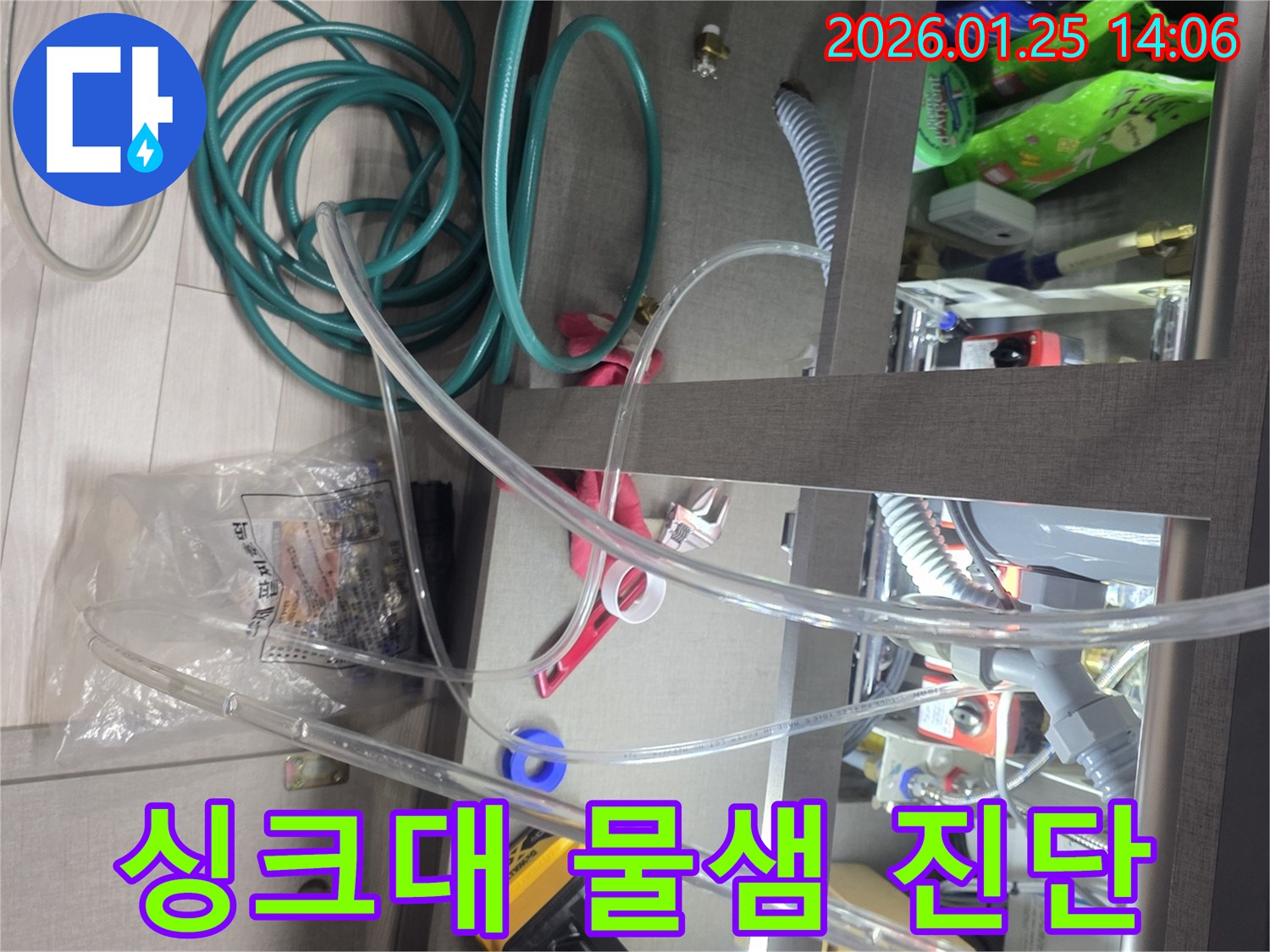 주방 싱크대 아래에서 발생하는 물샘 현상을 진단하기 위해-다양한 장비와 호스를 연결하여-누수 지점을 찾아내고 있는 현장입니다.