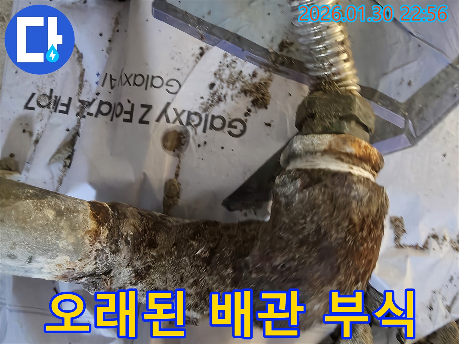 심하게 녹슬고 부식된 금속 배관의 엘보 연결부-누수가 발생하고 있음을 시사합니다.