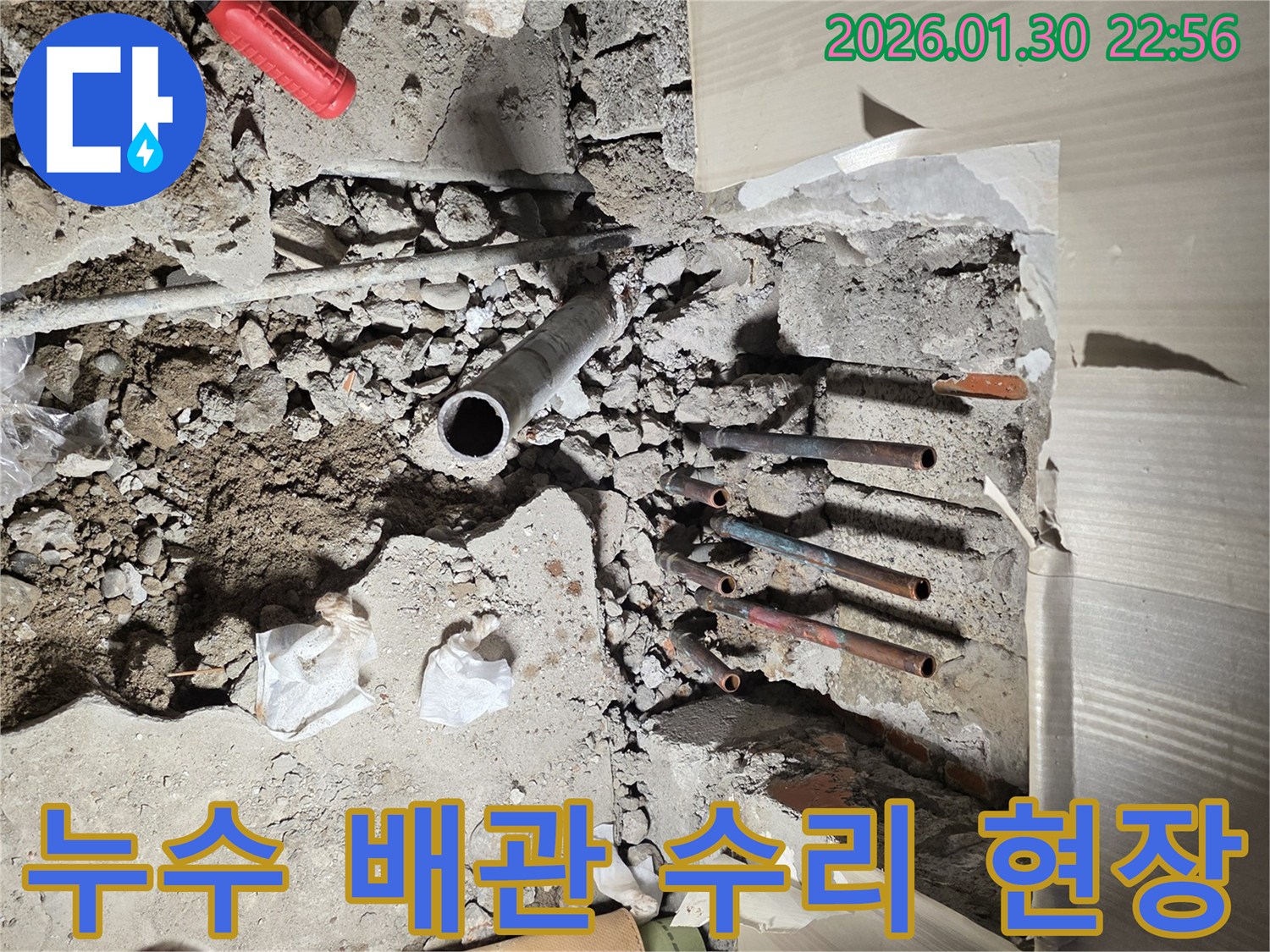이 이미지는-부천 역곡동의-누수 현장에서-바닥을 파쇄한 후-노출된 배관들을-수리하기 전-모습을 보여줍니다