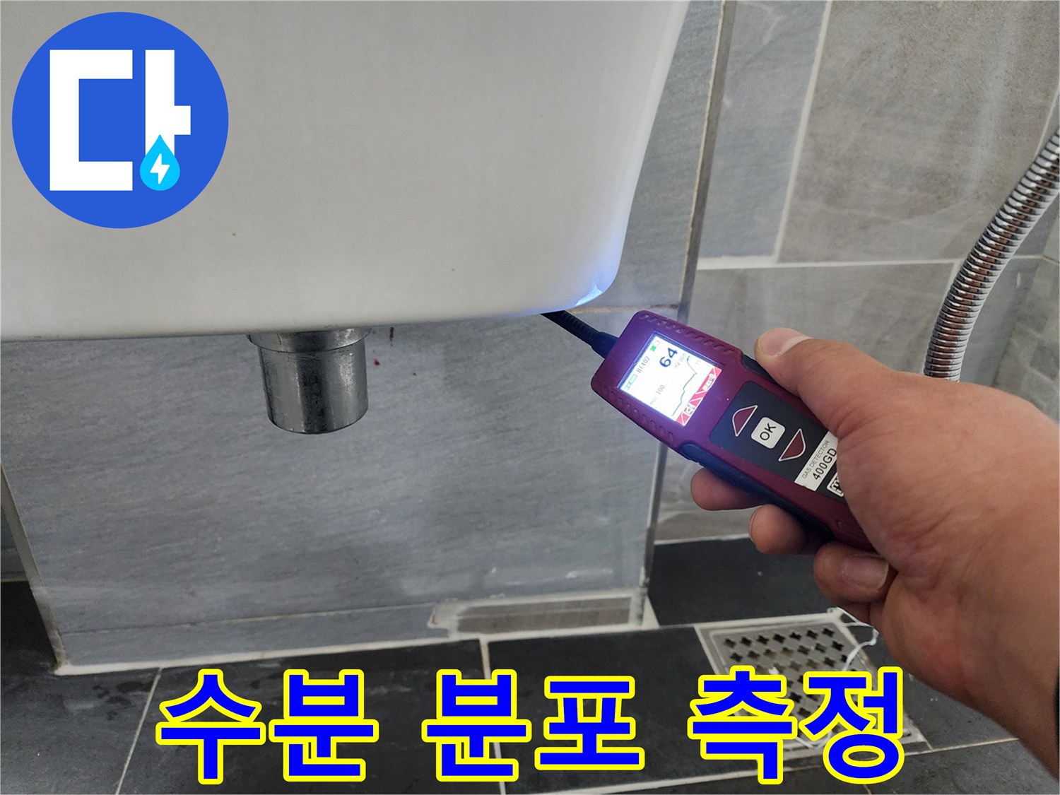 탐지기 수치를 통해 변기 옆 타일의 누수 여부를 검사하는 모습