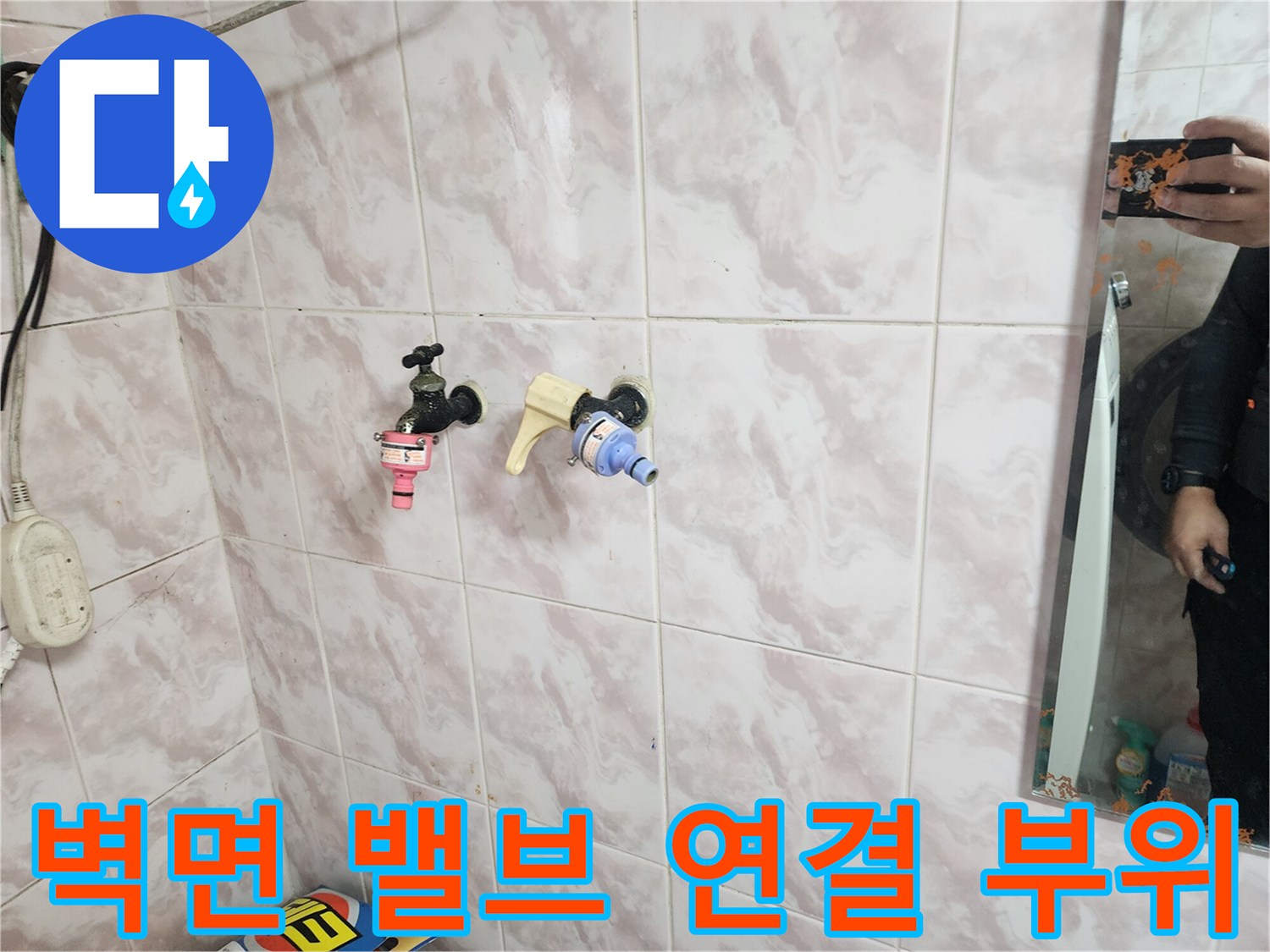 욕실 타일 벽면에 노출된 오래된 수도 밸브와 부속의 모습입니다.