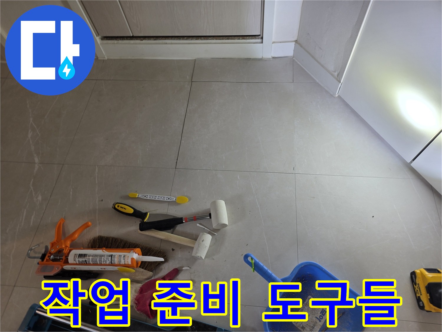 타일 바닥에 놓여있는 실리콘 건과 작업용 장갑 및 청소 도구