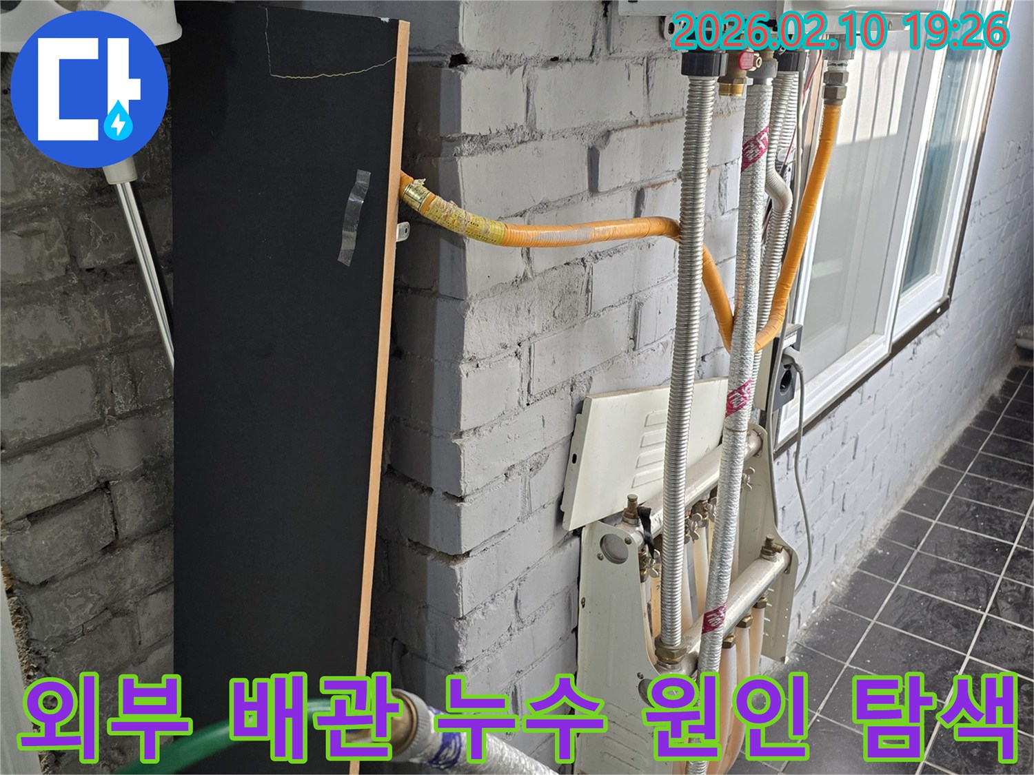 다세대주택 외벽의 복잡한 배관에서-누수 원인을 파악하기 위해-정밀하게 점검하는 장면