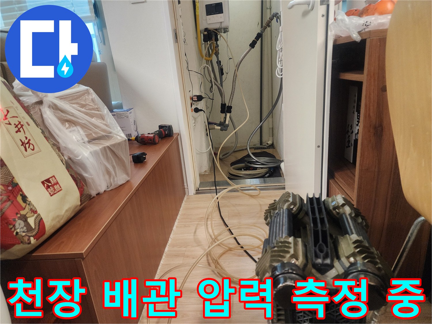 복잡한 구조의 천장 배관에 디지털 압력계를 연결하여 검사를 수행하는 모습입니다.