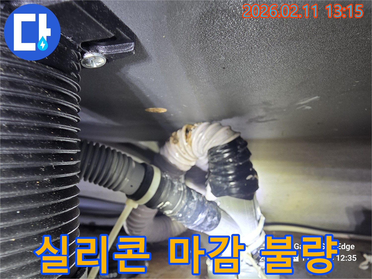배수관 연결 부위의 실리콘 마감이 불량하여 물이 새는 현장을 담은 사진입니다-실리콘의 손상과 물기가 보입니다