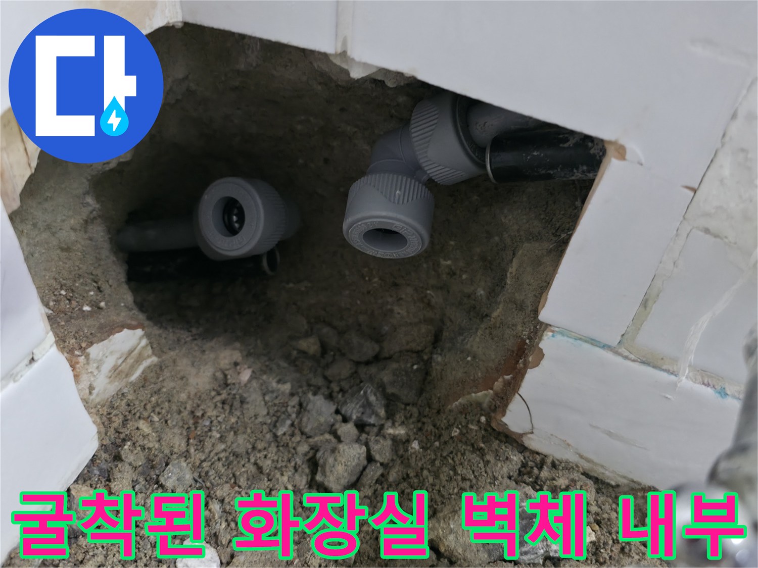 타일 제거 후 드러난 흙과 배관 연결 부속의 클로즈업 사진