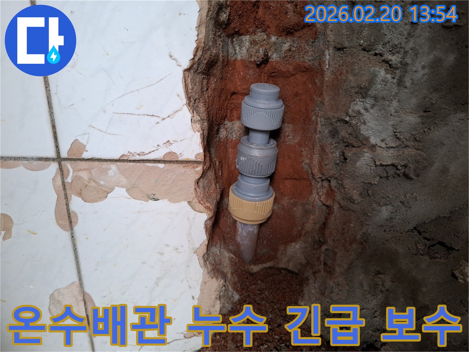 벽을 개방하여-드러난-온수배관의-누수 지점을-새로운 연결 부품으로-긴급하게-보수하는-작업 현장입니다.