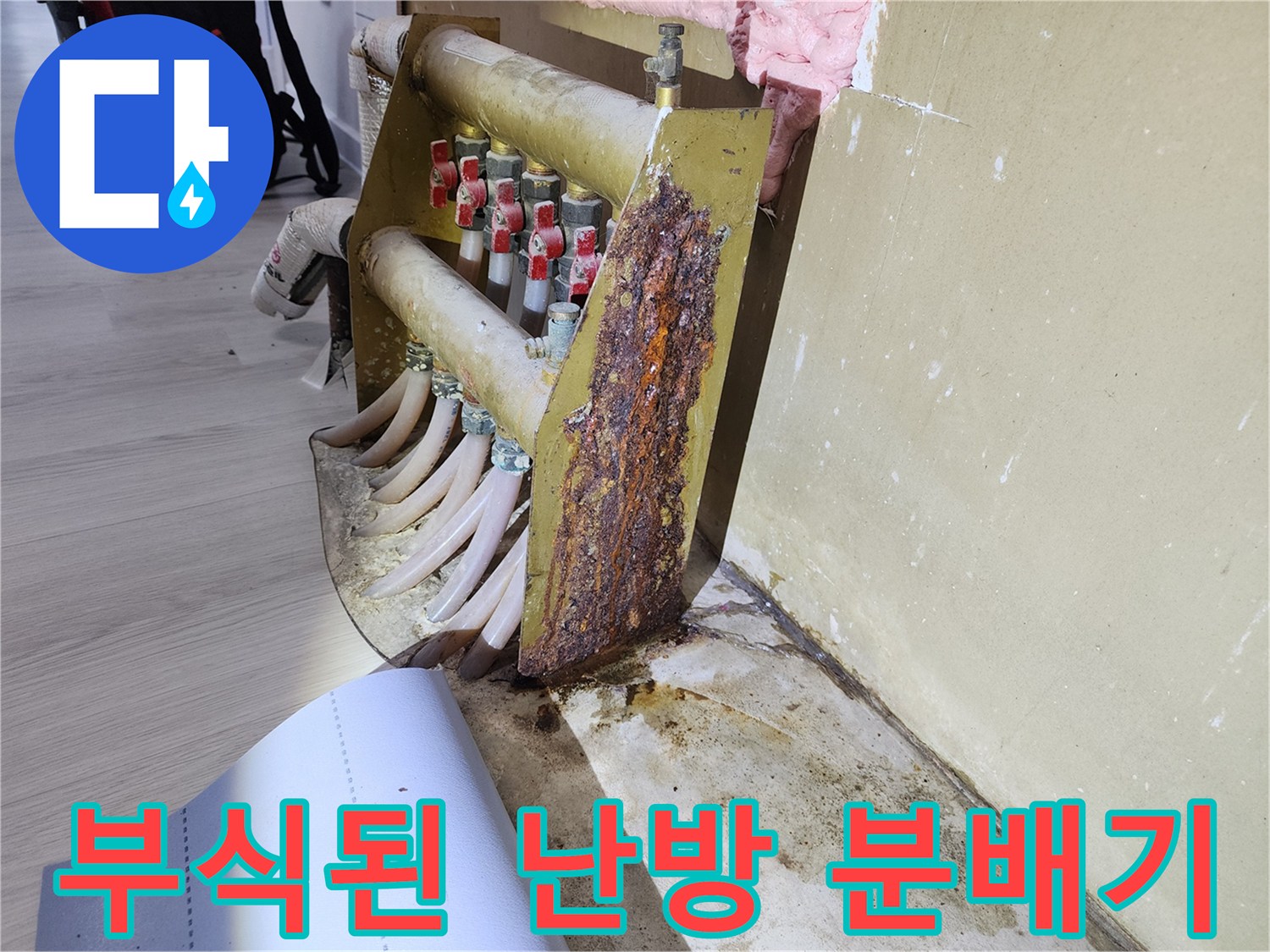심하게 부식되어 구멍이 뚫린 금속 재질의 난방 분배기 본체와 고정판 모습