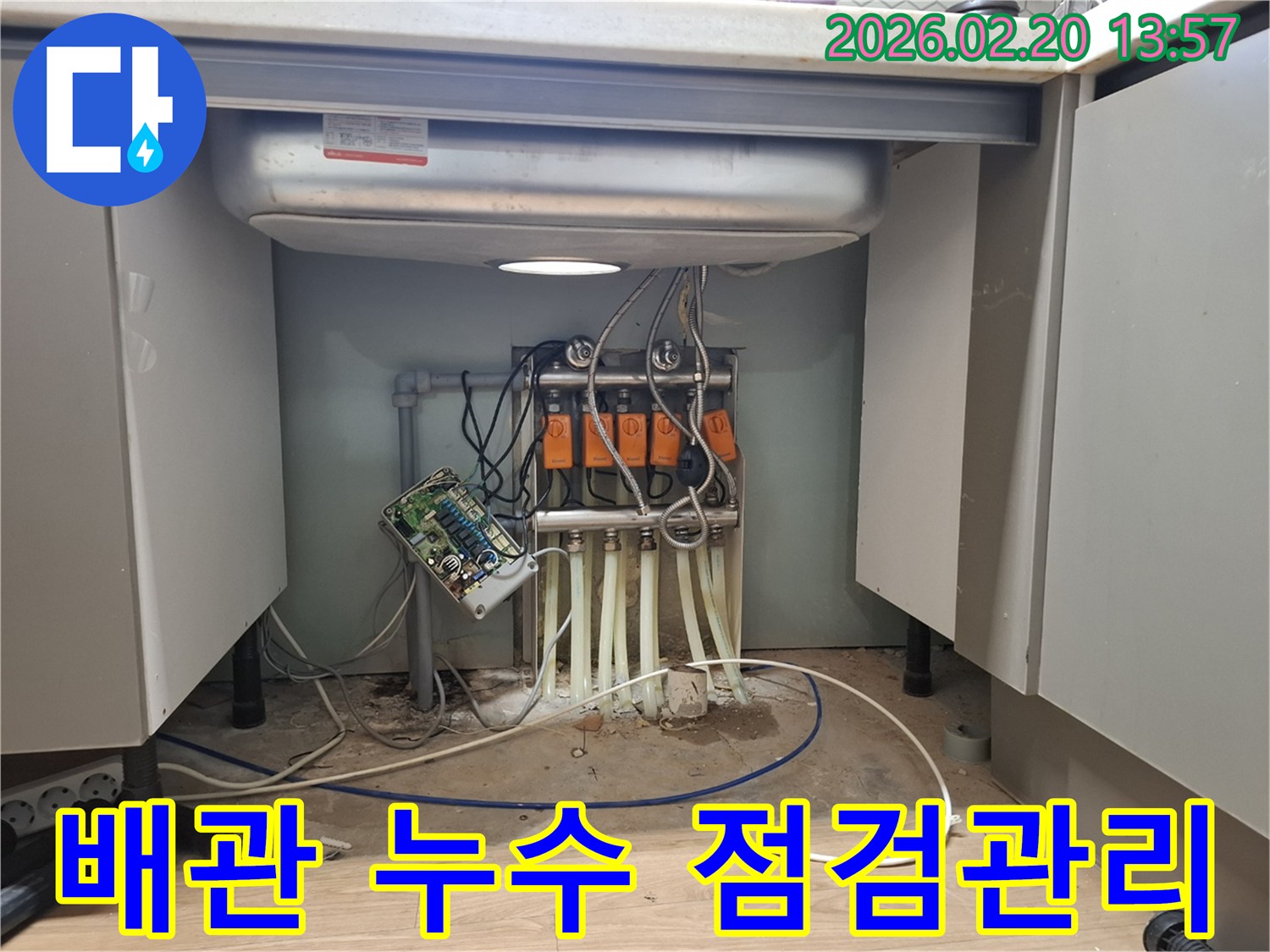 싱크대 하부의 복잡한 배관에서-누수가 발생하여-전문 엔지니어가 점검하고-향후 관리 방안을 안내하고 있습니다