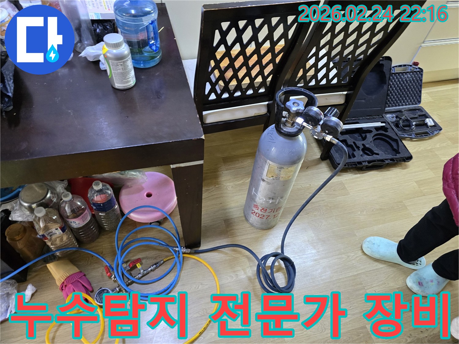 둔촌대로 누수 문제를 안심하고 해결하기 위해-전문가가 가스통과 압력 게이지를 연결하여-탐지 장비를 세팅하는 모습입니다