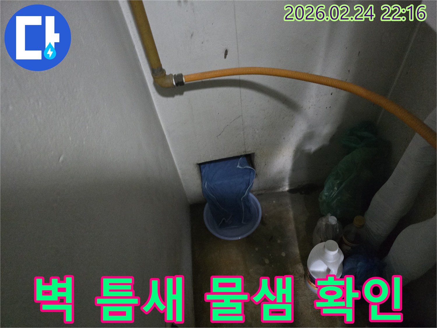 벽-하단부-구멍에서-물이-새어-나와-임시-용기에-받아지고-있는-누수-발생-장면
