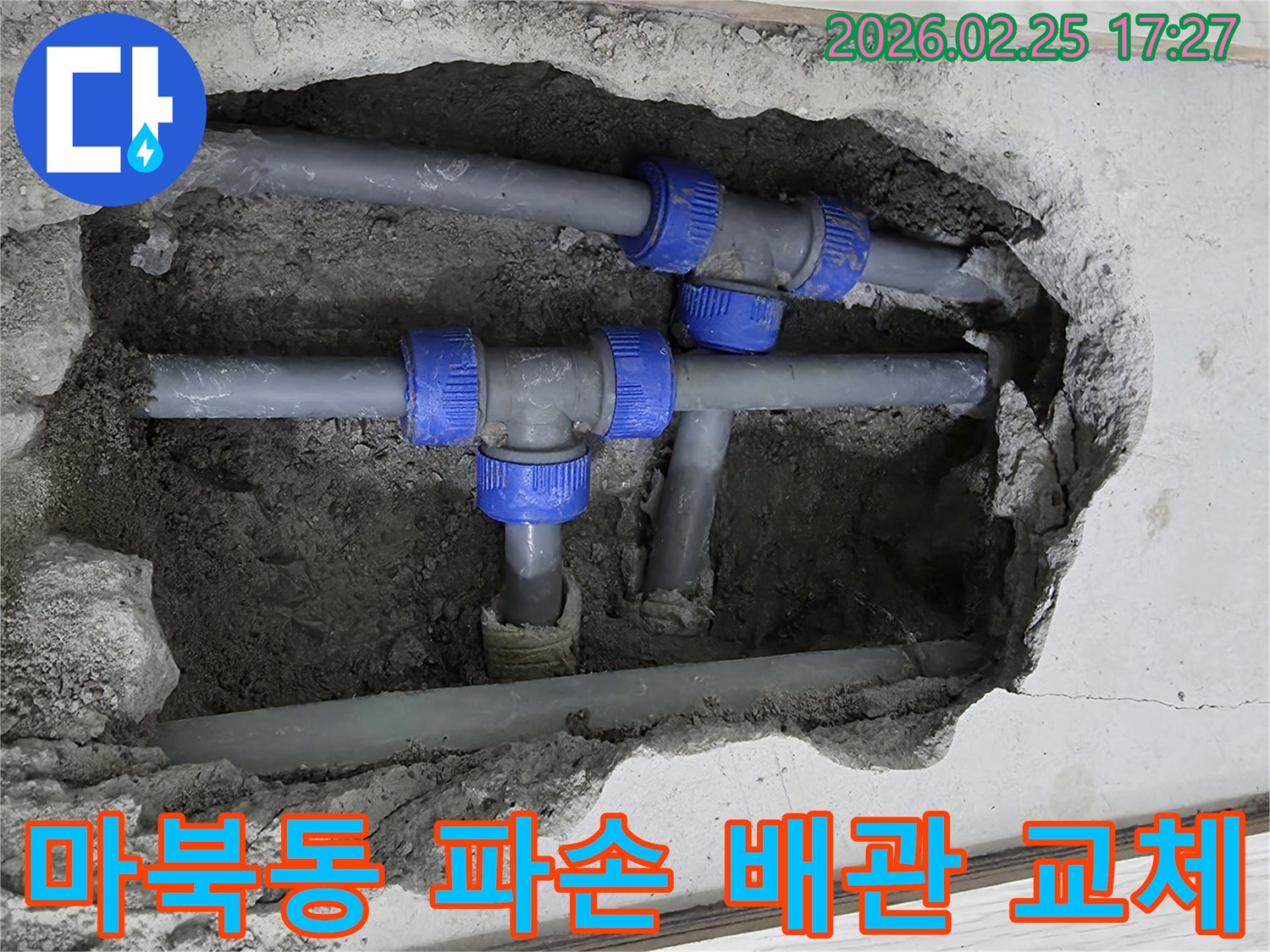 콘크리트 바닥을 깨고 드러난-파란색 연결 부속이 있는 파손된 회색 배관-새 배관으로 교체하기 전의 모습