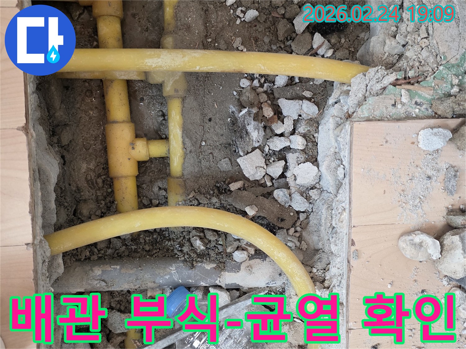 배관 누수 해결을 위해 바닥을 파쇄하고-노출된 오래된 배관의 부식 및 균열 상태를-정밀하게 확인하는 작업 현장입니다.