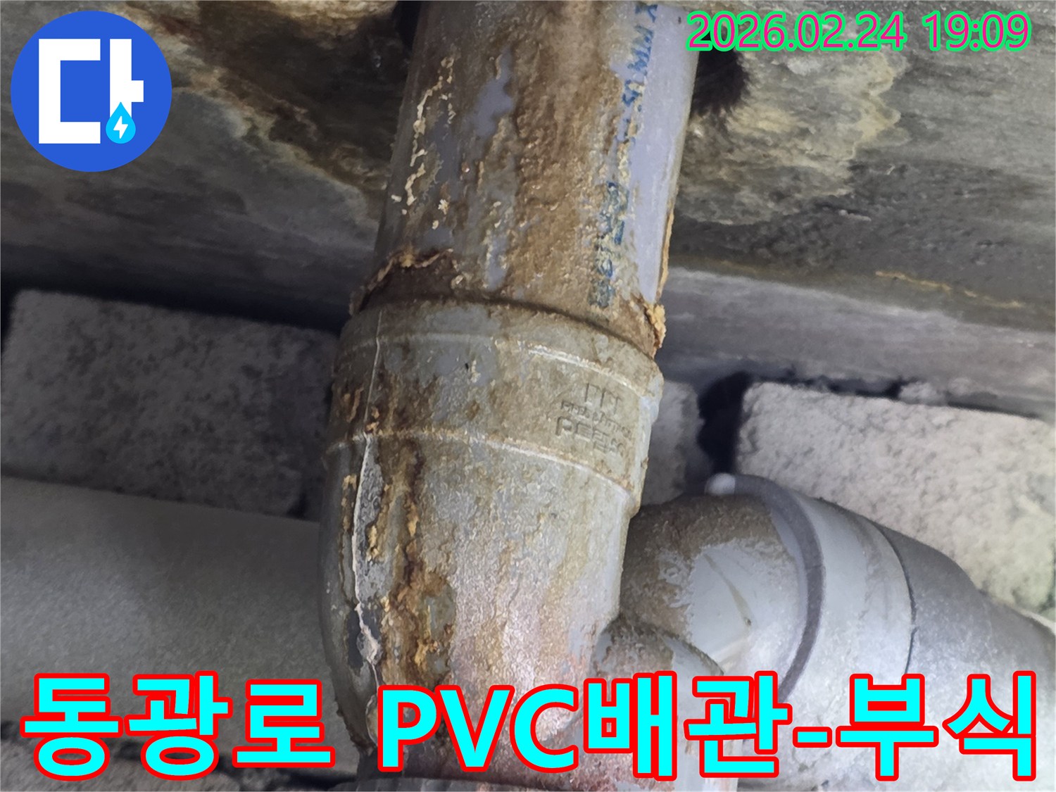 오래된 PVC 배관의-연결 부위에서-누수가 발생하여-부식된 물때가-벽면을 타고-흐르는 모습입니다.