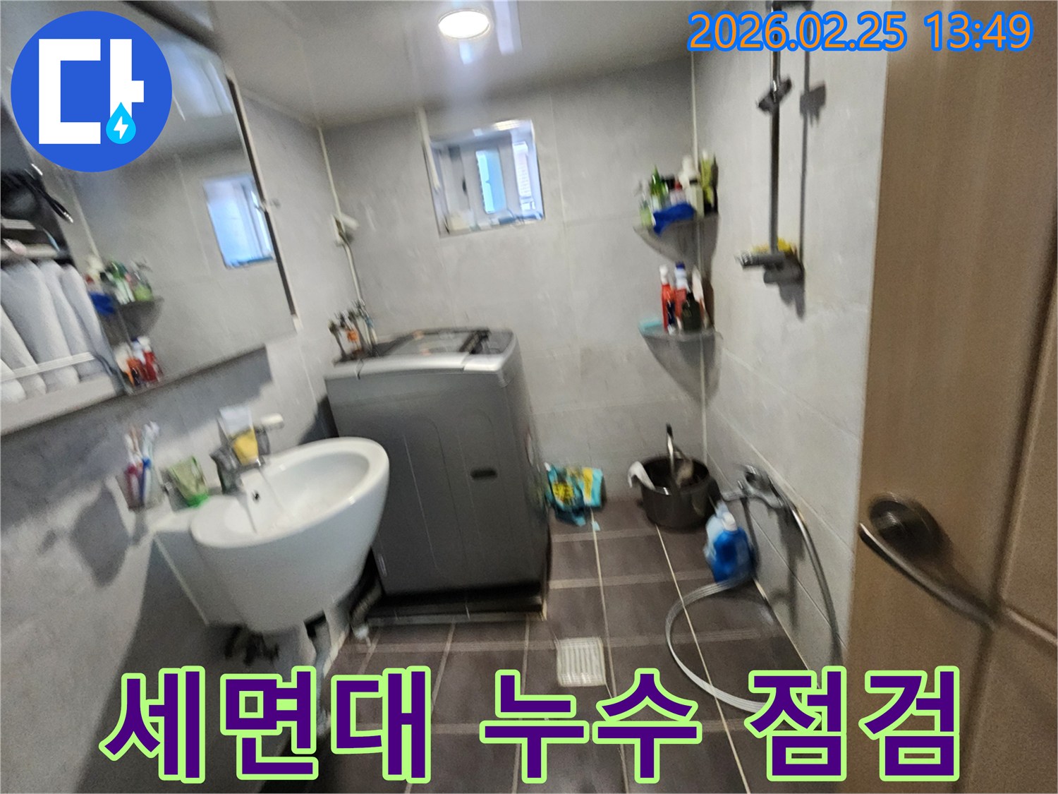 세면대와-세탁기가-있는-욕실에서-세면대-아래-누수-여부를-점검하는-모습을-담은-사진