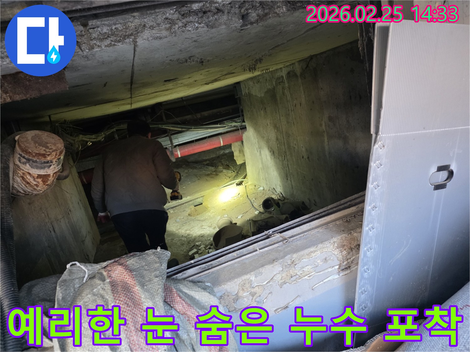 누수 전문 엔지니어가-어둡고 협소한 공간에서-손전등을 비춰가며-육안으로 확인하기 어려운-숨겨진 누수 흔적을-예리하게 찾아내는 모습입니다.