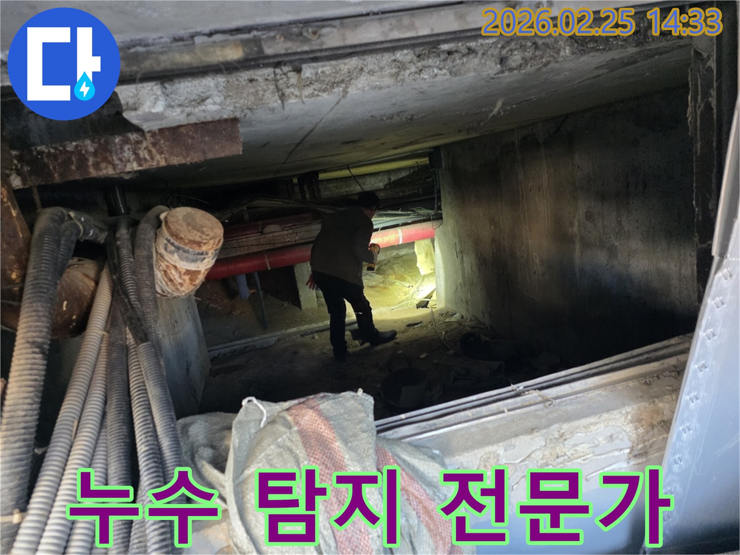 누수 전문가가-손전등을 비추며-배관이 복잡한-지하 통로를-조사하는 모습
