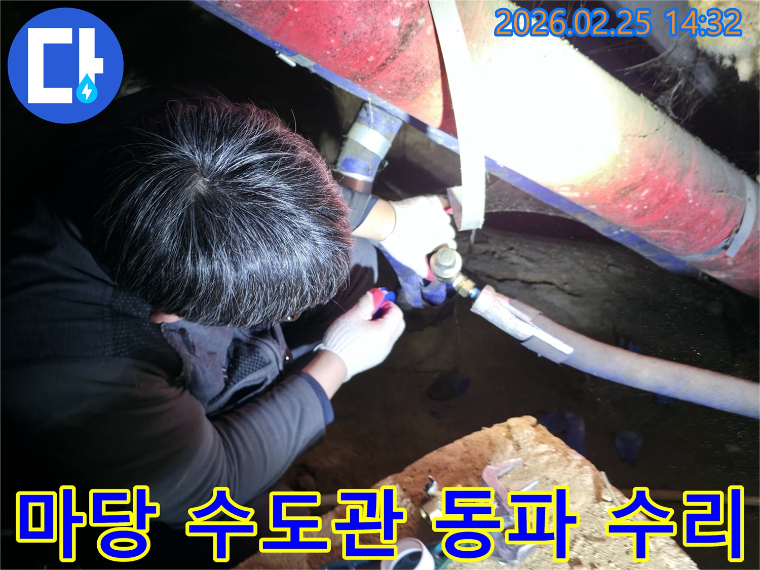 숙련된 누수 기술자가 좁은 공간에서 손전등을 비추며 마당-수도관 동파 후 누수 지점을 정밀하게 점검하고-꼼꼼하게 수리하고 있습니다-수도누수해결-전문가수리