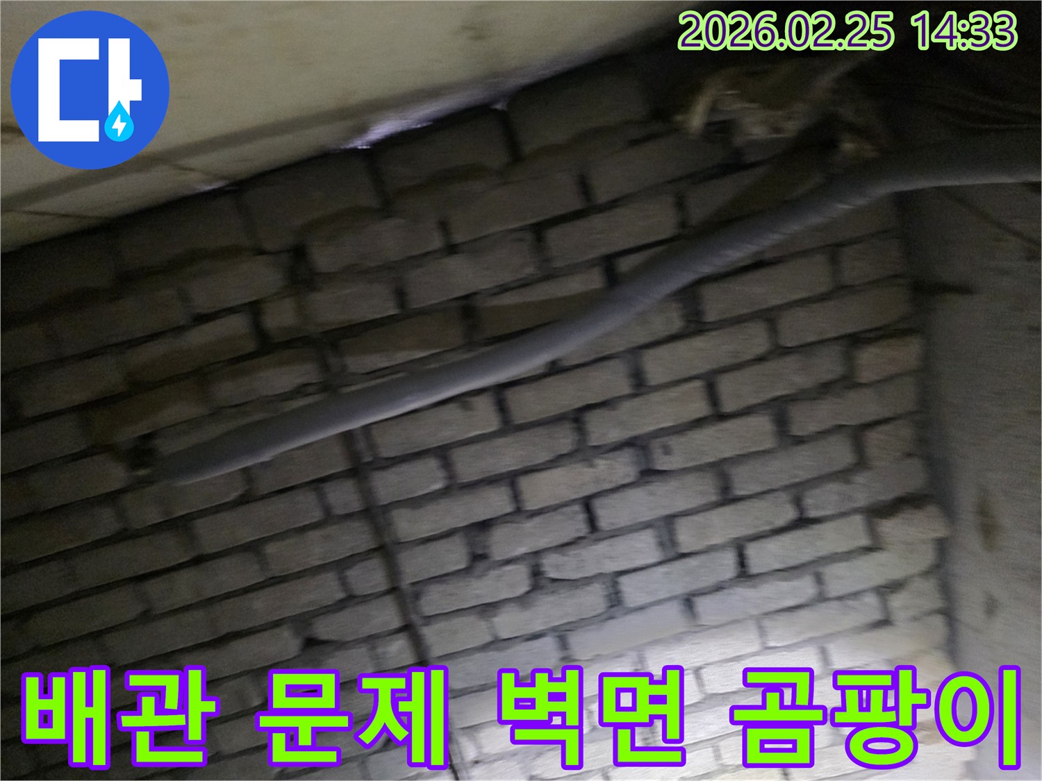 어두운 벽돌 벽면을 배경으로-단열된 배관과 함께-누수로 인한 벽면 곰팡이를-제거하기 위해 검사되는 현장 모습입니다.