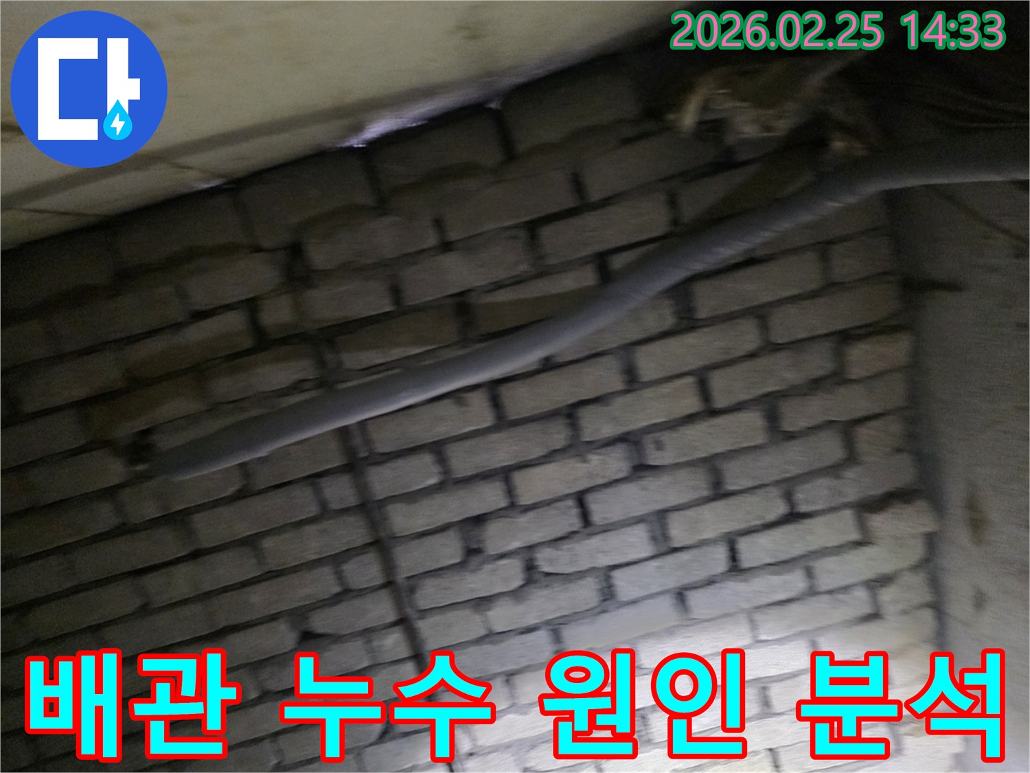 어두운 벽돌 벽면을 배경으로-단열재로 감싸인 배관에서-누수 원인을 정밀하게-분석하기 위해 촬영된 현장 이미지입니다.