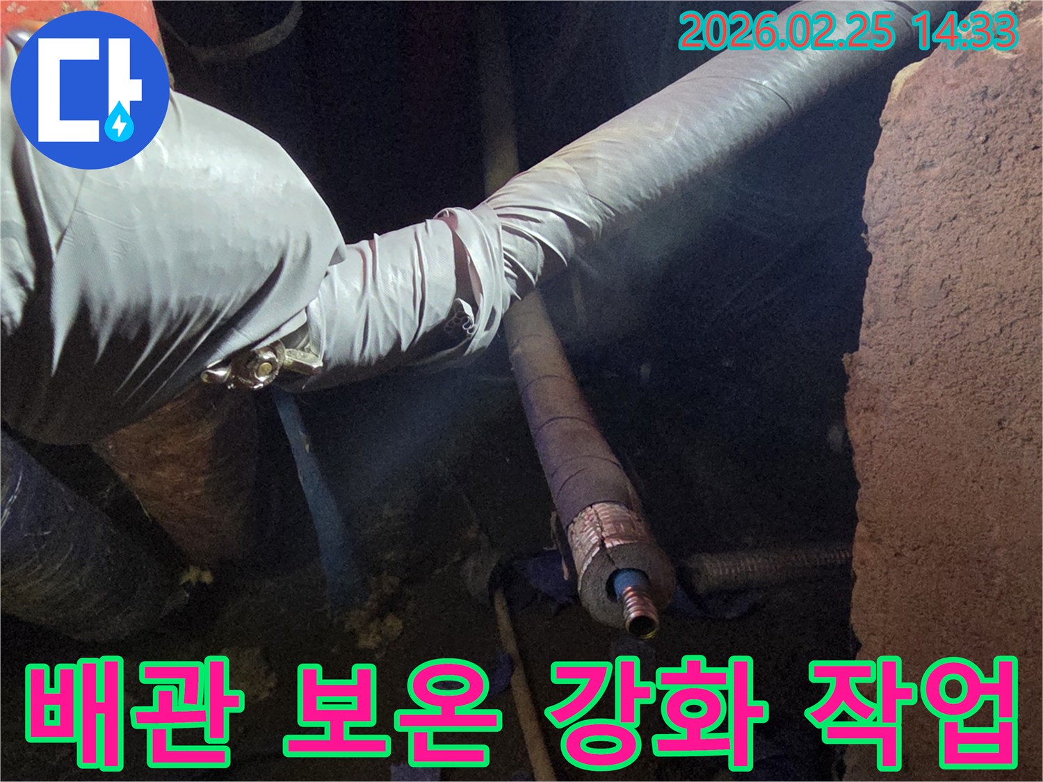 어두운 작업 공간에서-장갑을 낀 손이-배관에 새로운-보온재를 꼼꼼하게-감싸서-겨울철 동파를-예방하는-모습입니다