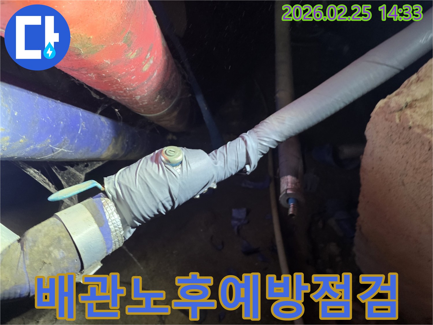 이 이미지는 누수 탐지를 위해 배관에 압력 측정 장비를 연결하는 전문 엔지니어의 모습을 보여줍니다-정확한 누수 지점을 찾기 위한 핵심 과정입니다