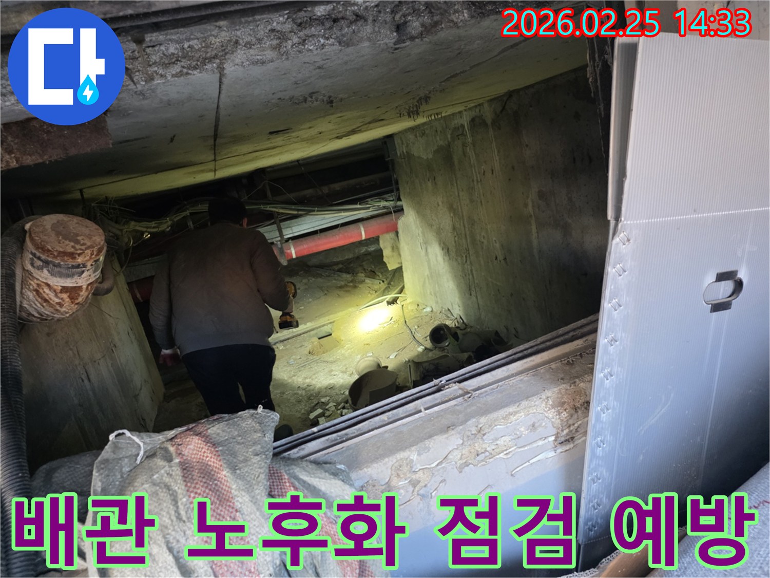 전문 누수 엔지니어가-손전등을 들고-어둡고 좁은 지하 공간에서-배관의 노후화 및 부식 여부를-집중적으로 관찰하여-미래의 누수를 예방하는 장면입니다.