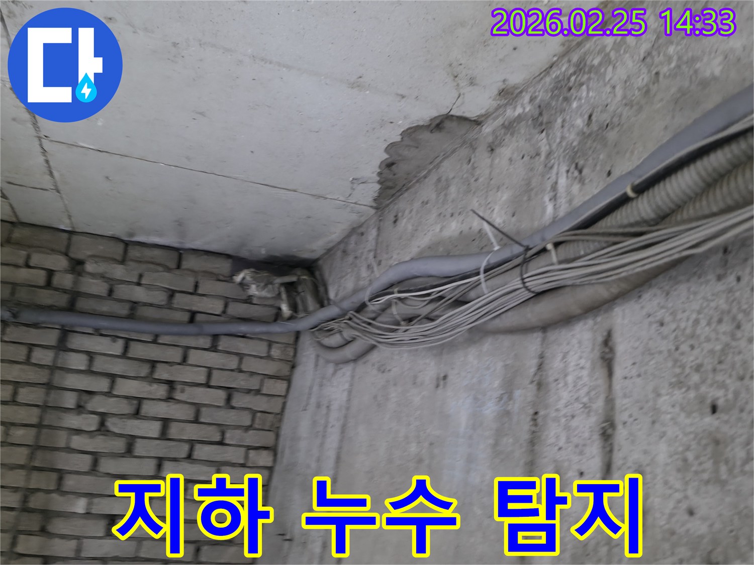 지하 벽면의-콘크리트와-벽돌 벽이 만나는-지점에서-발견된-오랜 누수로 인한-물자국과-주변의 복잡한 배관