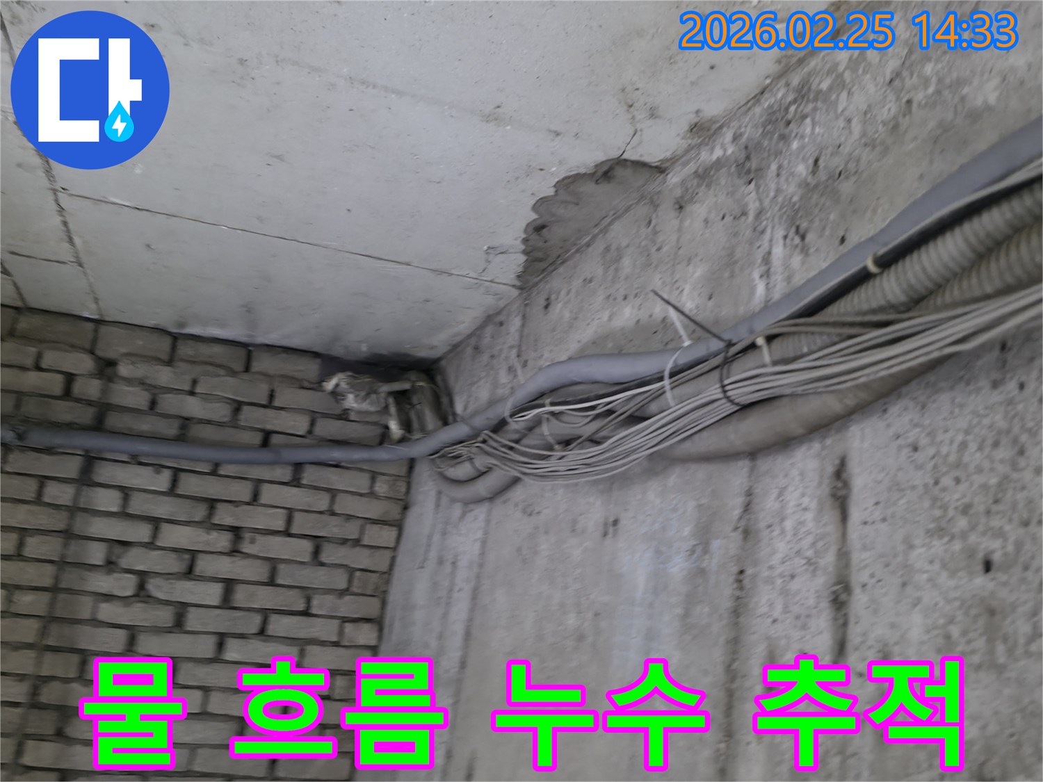 지하 벽면의-콘크리트와-벽돌 벽이 만나는-지점에서-발견된-오랜 누수로 인한-물자국과-주변의 복잡한 배관