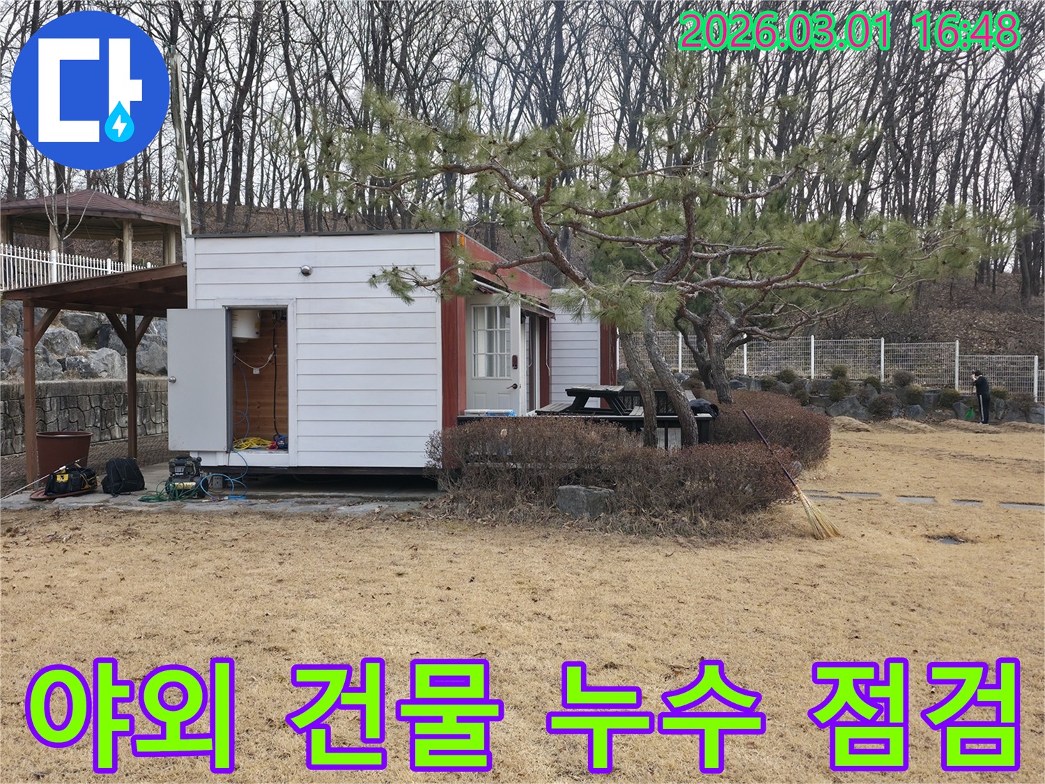 광적면의 야외 건물에서-누수 엔지니어가-외부 환경에 강한 탐지 장비를-설치하고 점검하는 모습입니다.