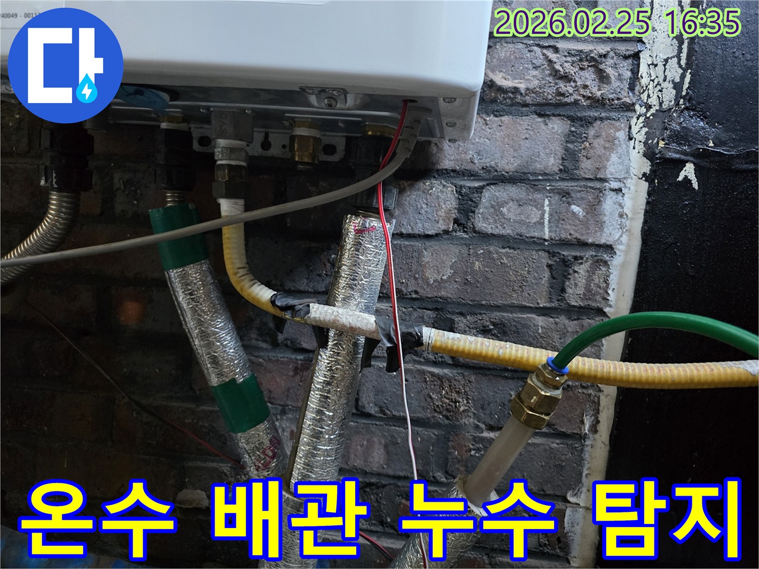 이 이미지는-보일러 하단에-연결된-온수 배관과-다른 배관들을-보여주며-온수 누수 여부를-확인하기 위한-정밀한 탐지가-진행되고-있음을-암시합니다.