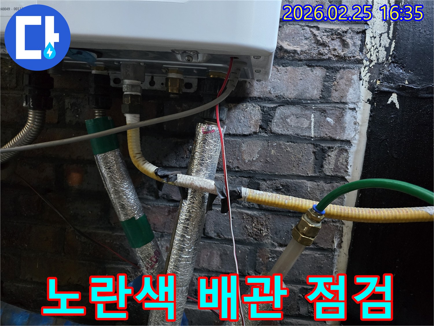 이 이미지는-보일러 하단에서-연결된-노란색 주름관과-다른 배관들의-연결 상태를-보여주며-특정 배관의-누수 여부를-확인하는-장면입니다.