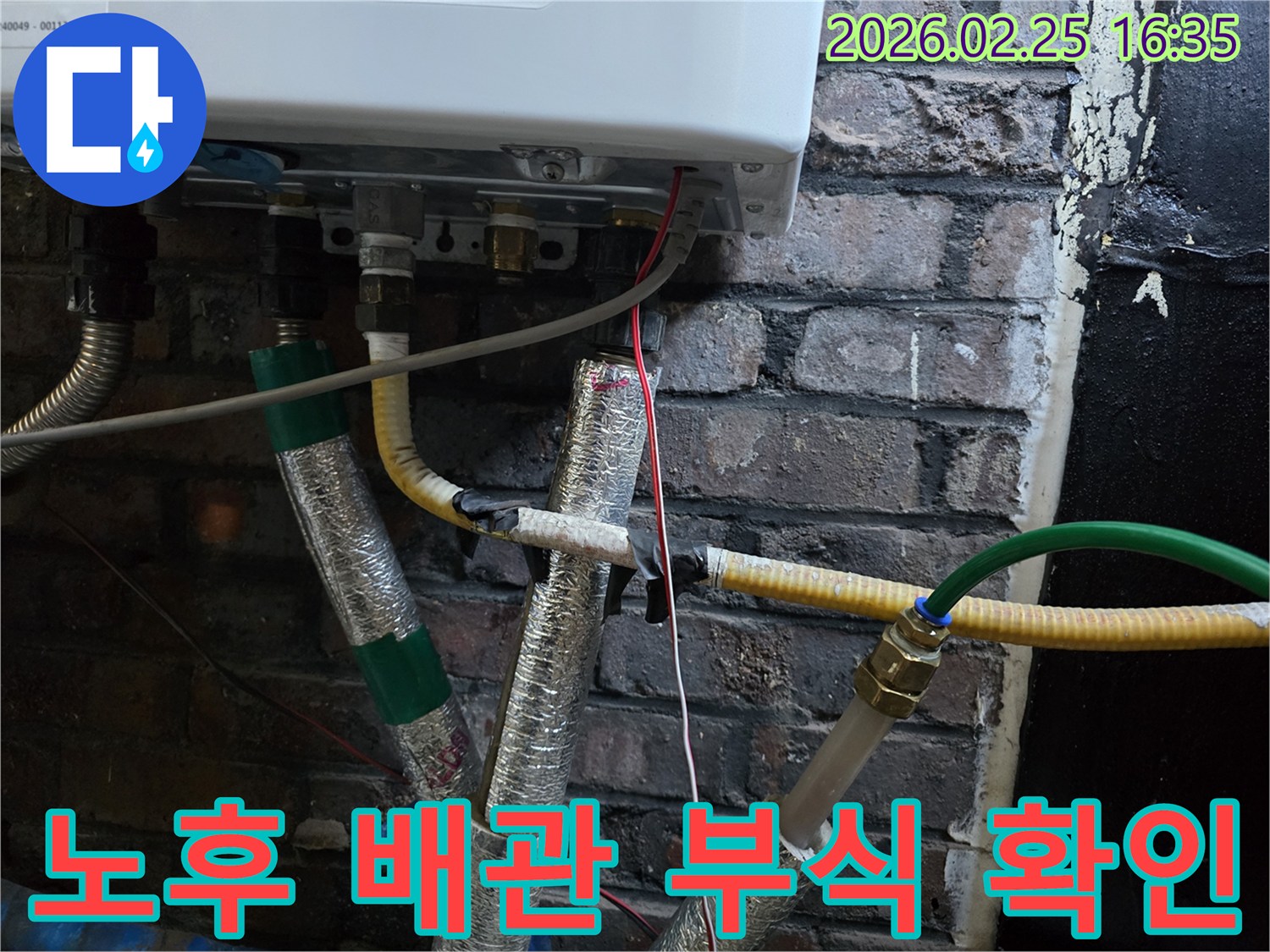 이 이미지는-오래된 벽돌 벽에-설치된-보일러 하부의-노후된 배관과-부식 흔적을-보여주며-배관 교체의-필요성을-시사합니다.