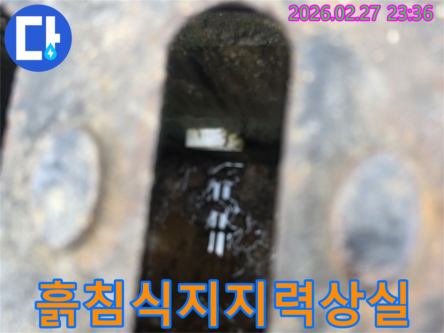 녹슨-철제-격자-아래-어두운-공간에-고인-물과-물속에-잠긴-배관-주변-흙-침식-흔적이-보이는-누수-현장