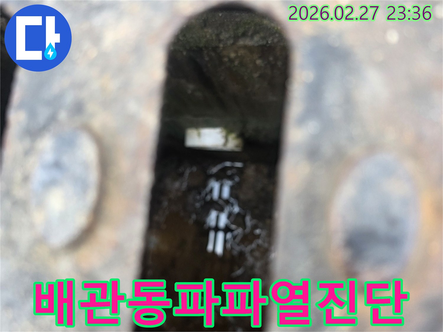 녹슨-철제-배수구-아래-고인-물과-물속에-비치는-배관-파열-흔적이-보이는-누수-현장-사진