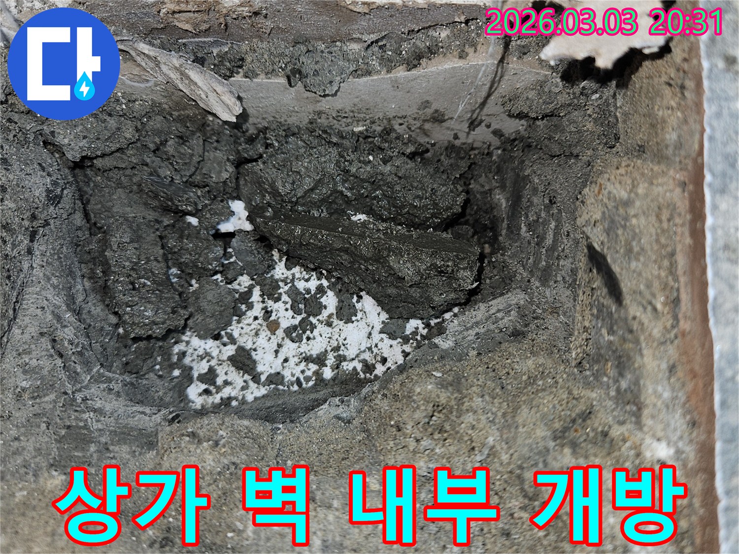 상가 벽면 누수 원인을 정확히 찾기 위해 벽면을 조심스럽게 개방한 모습입니다-내부의 젖은 시멘트와 부식된 흔적이 보입니다.