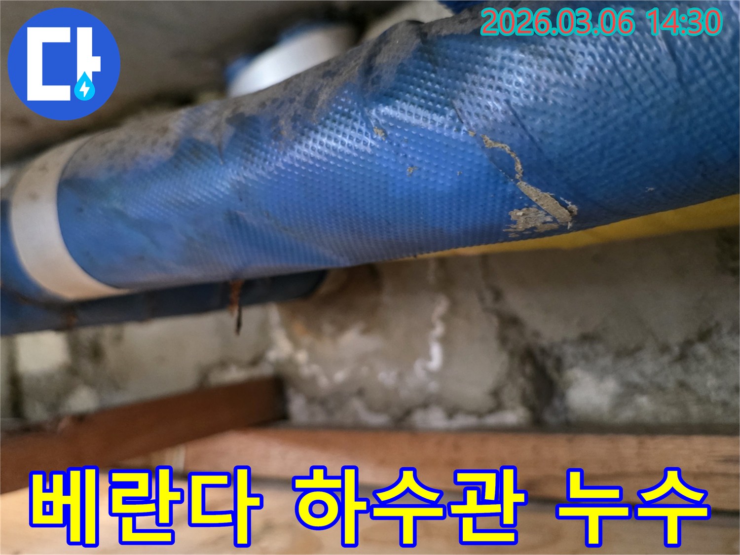 빌라 베란다 하부-파란색 배관과-젖은 콘크리트 벽면-그리고 나무 지지대를-정밀하게 점검하는 모습